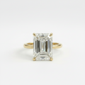 Gold ring with a large emerald-cut diamond on a white background