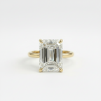 Gold ring with a large emerald-cut diamond on a white background