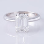 Silver ring with a large emerald-cut diamond on a light gray background