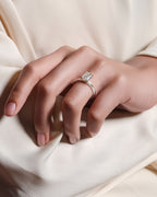 Close-up of a hand wearing a diamond ring on a light fabric background