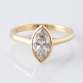 Gold ring with a marquise-shaped diamond on a light gray background