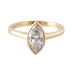 Gold ring with a marquise-shaped diamond on a light gray background
