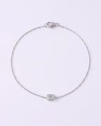 A delicate silver chain bracelet with a small rectangular clear gemstone centerpiece, displayed on a clean white background.