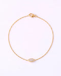 A delicate yellow gold chain bracelet with a small marquise-shaped clear gemstone centerpiece, displayed on a clean white background.