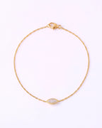 A delicate yellow gold chain bracelet with a small marquise-shaped clear gemstone centerpiece, displayed on a clean white background.