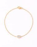 A delicate yellow gold chain bracelet with a small oval bezel-set clear stone, displayed on a clean white background.