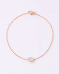 A delicate gold chain bracelet with a small teardrop-shaped clear gemstone pendant, displayed on a clean white background.
