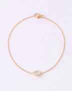 A delicate gold chain bracelet with a small teardrop-shaped clear gemstone pendant, displayed on a clean white background.