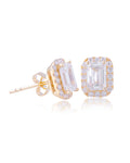 A pair of yellow gold halo stud earrings featuring large emerald-cut clear stones surrounded by smaller accent stones, shown on a clean white background with a soft reflection.